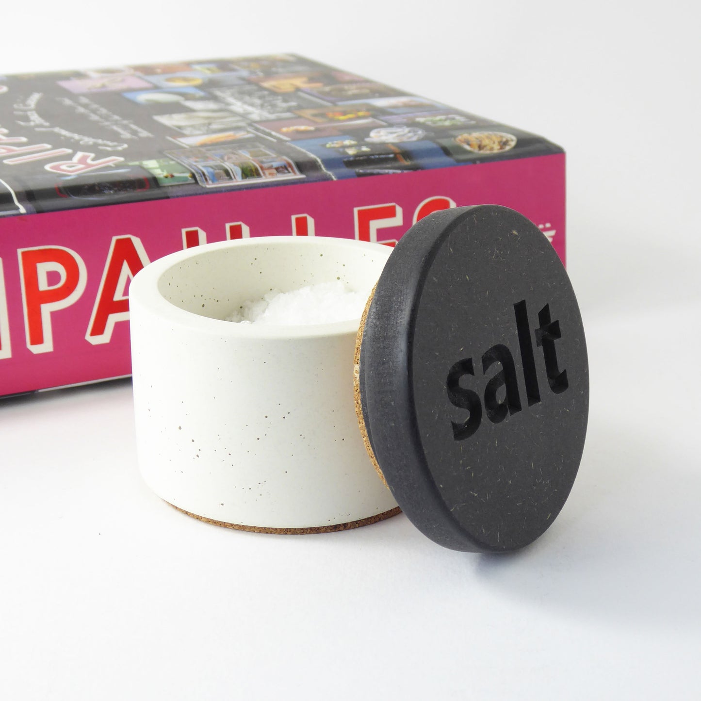 White concrete pot contained salt flakes with a black wooden lid with the word salt engraved on it