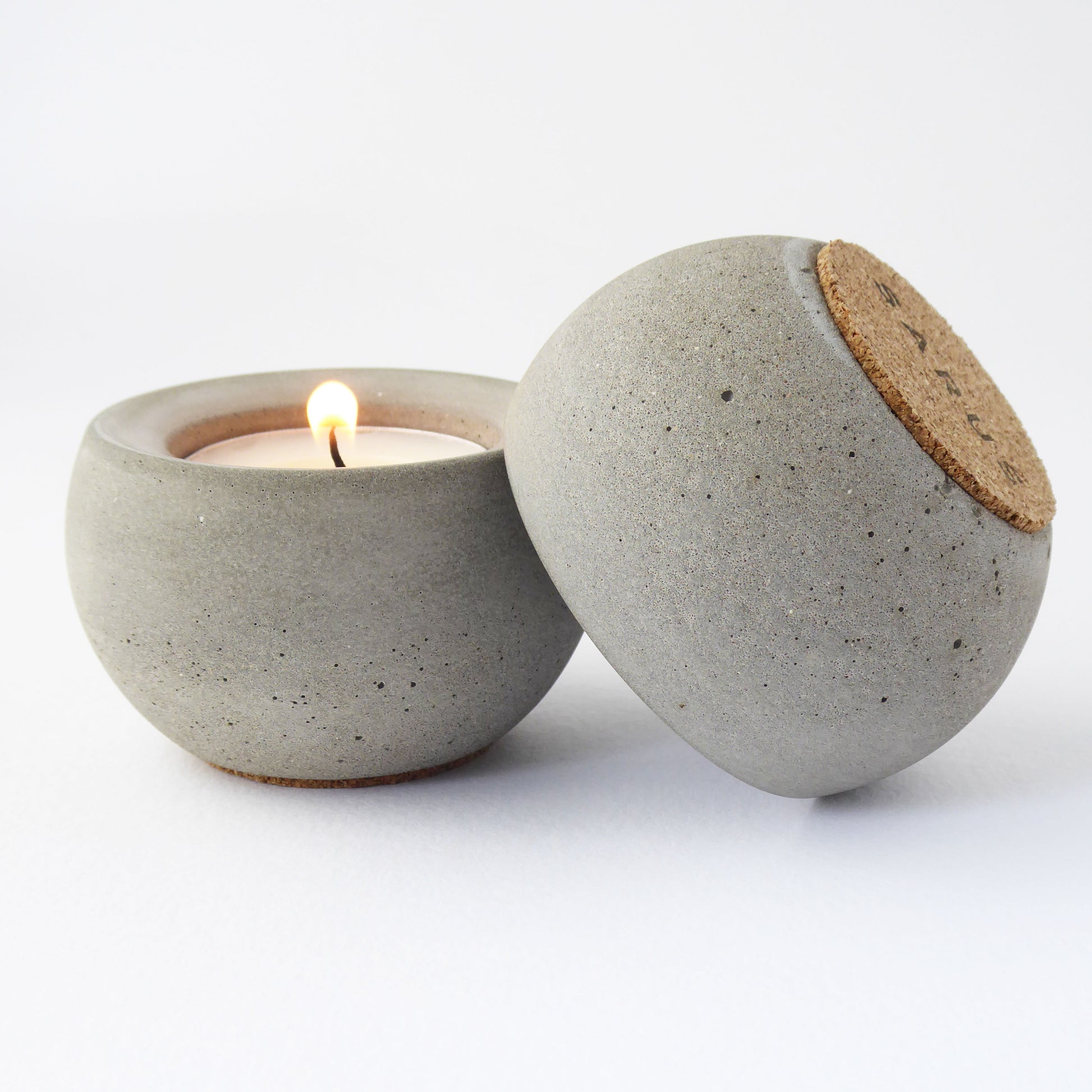 grey concrete candle holder with a lit candle on a white background