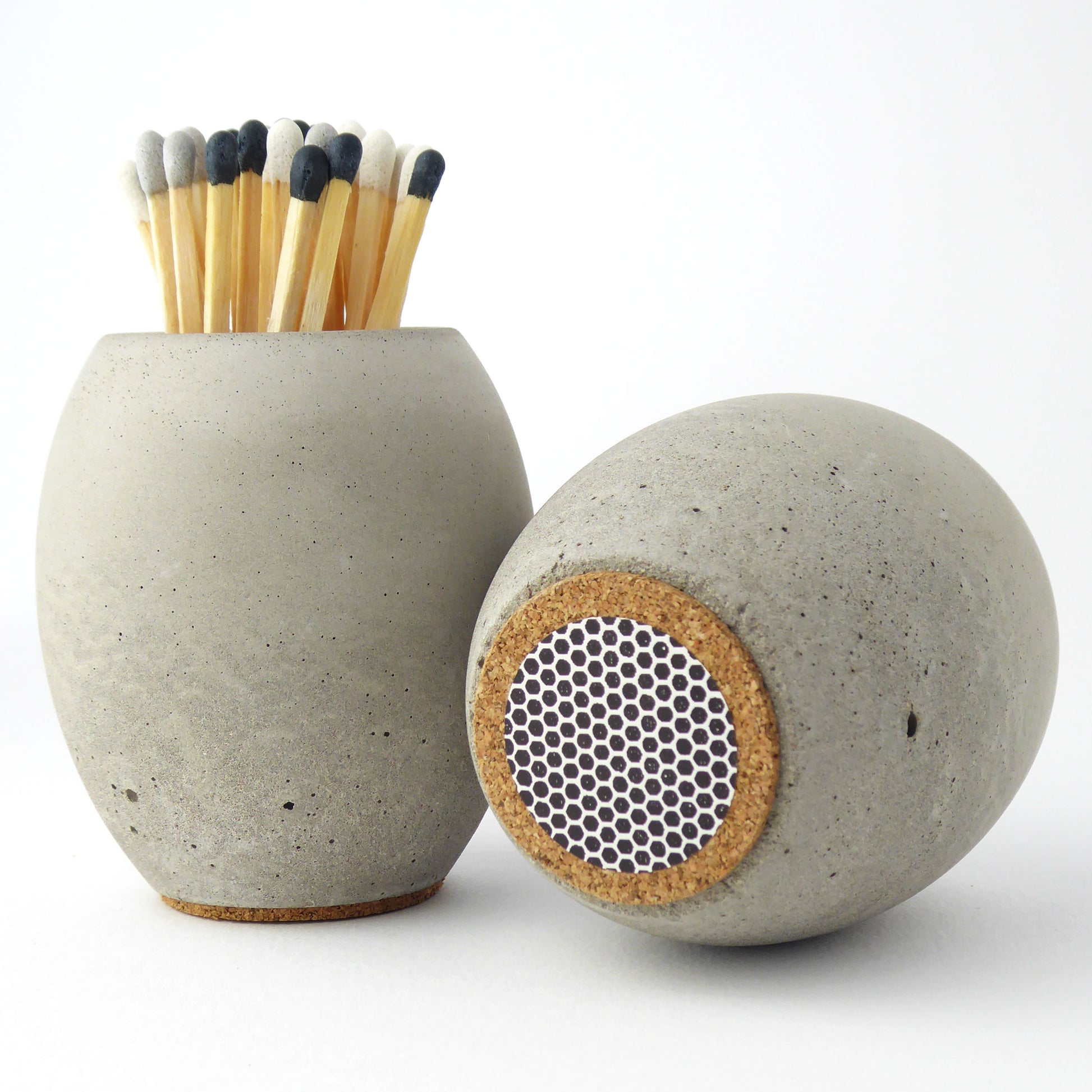 Grey concrete match holder with long matches and another match pot showing the base of the pot with its match striker pad