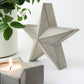 Concrete decorative star and star shaped candle holder with a lit candle on a white background