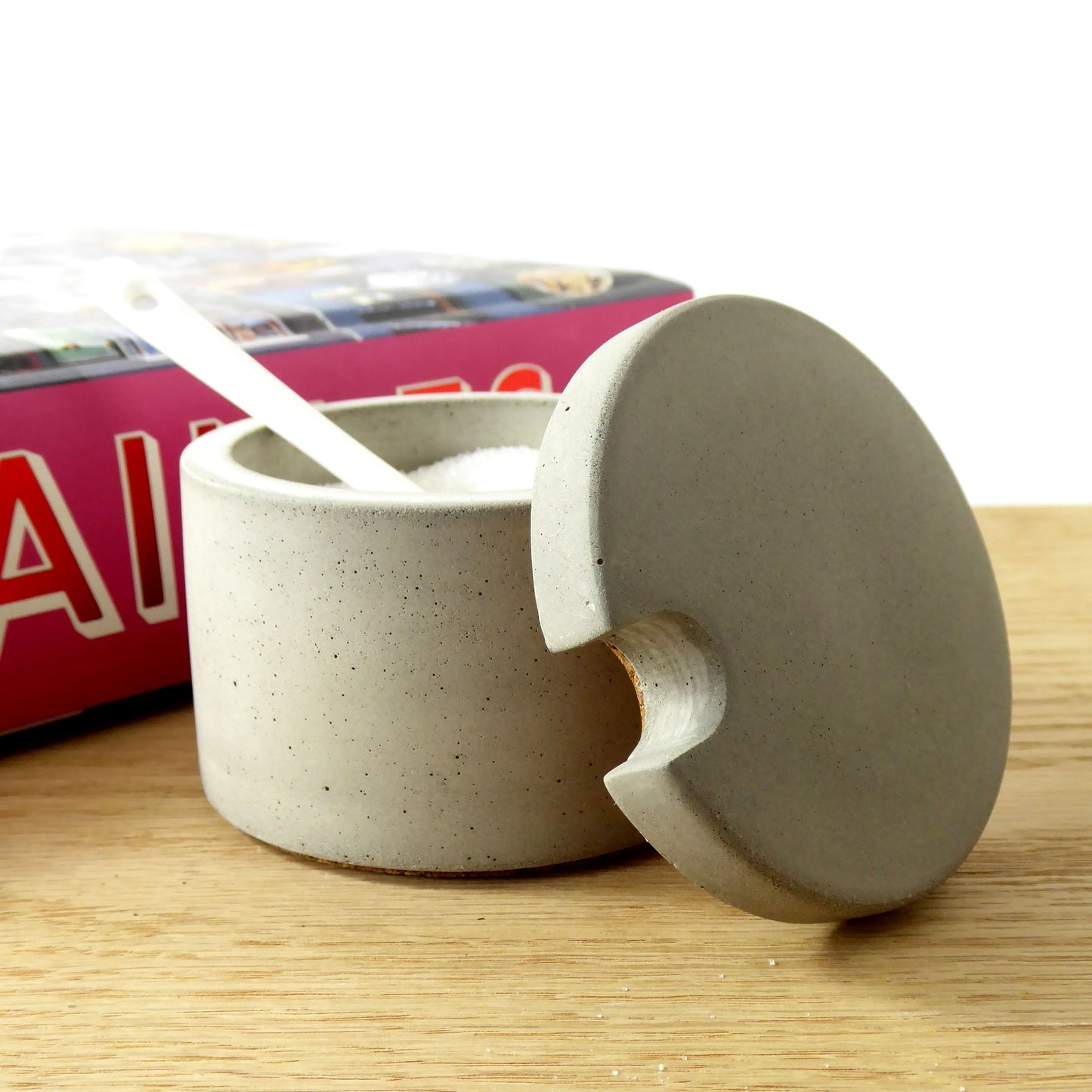 Grey concrete pot filled with salt and a white ceramic spoon