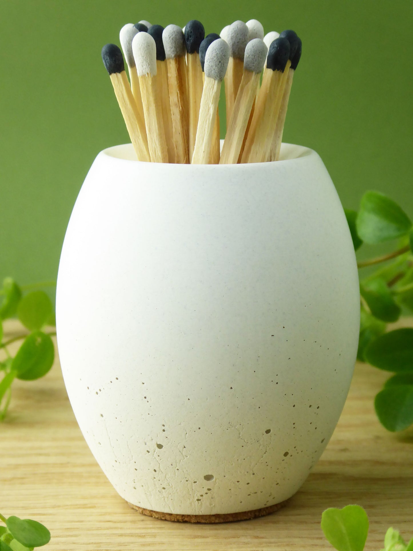 White concrete match pot with long matches on a green background