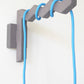 Gray wall-mounted hook with a blue plug in pendant light cable on a white background